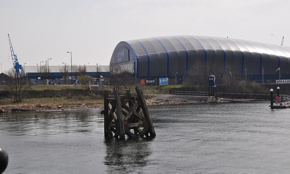 Cardiff Bay waterfront, with the arena behind the old timber dolphin in the water